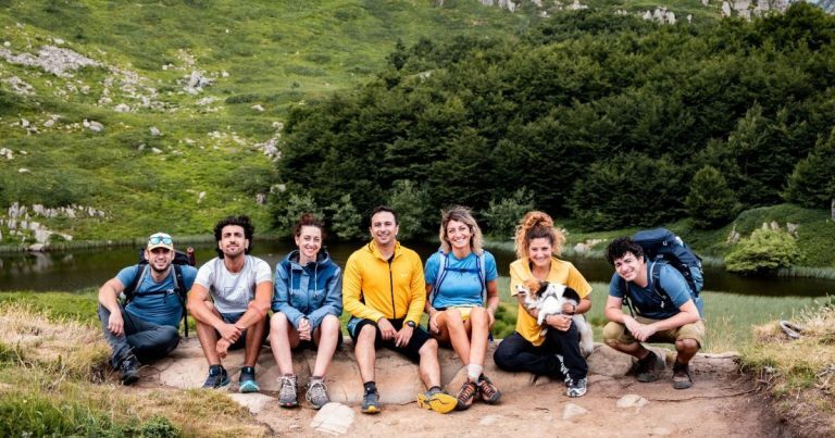 Corsisti seduti su un prato in montagna durante un'escursione